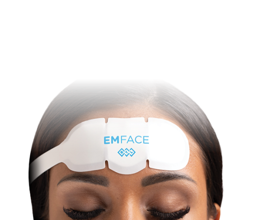 A person's forehead with a white EMFACE device applied. The eyes are closed, suggesting relaxation. The background is black, highlighting the device.