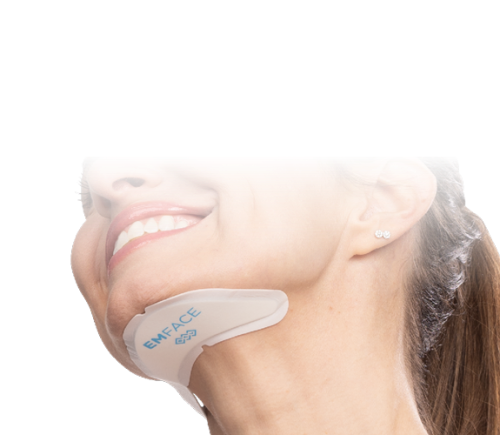 A woman with a subtle smile wears a contouring device labeled "EMFACE" on her jawline. The background is dark, drawing focus to her face.